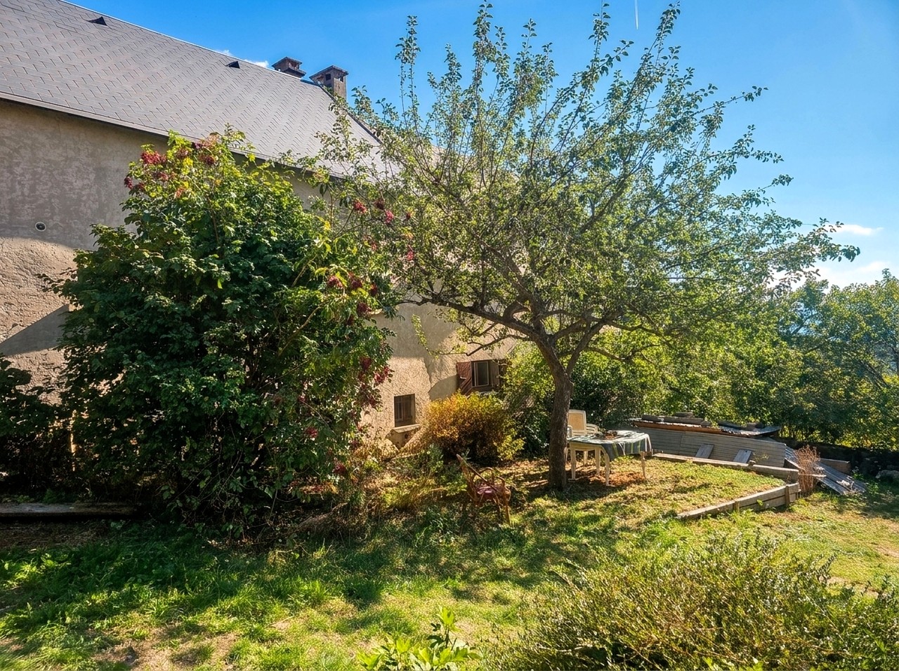 Jardin arboré avec pommier et terrasse d’une maison à vendre en Matheysine